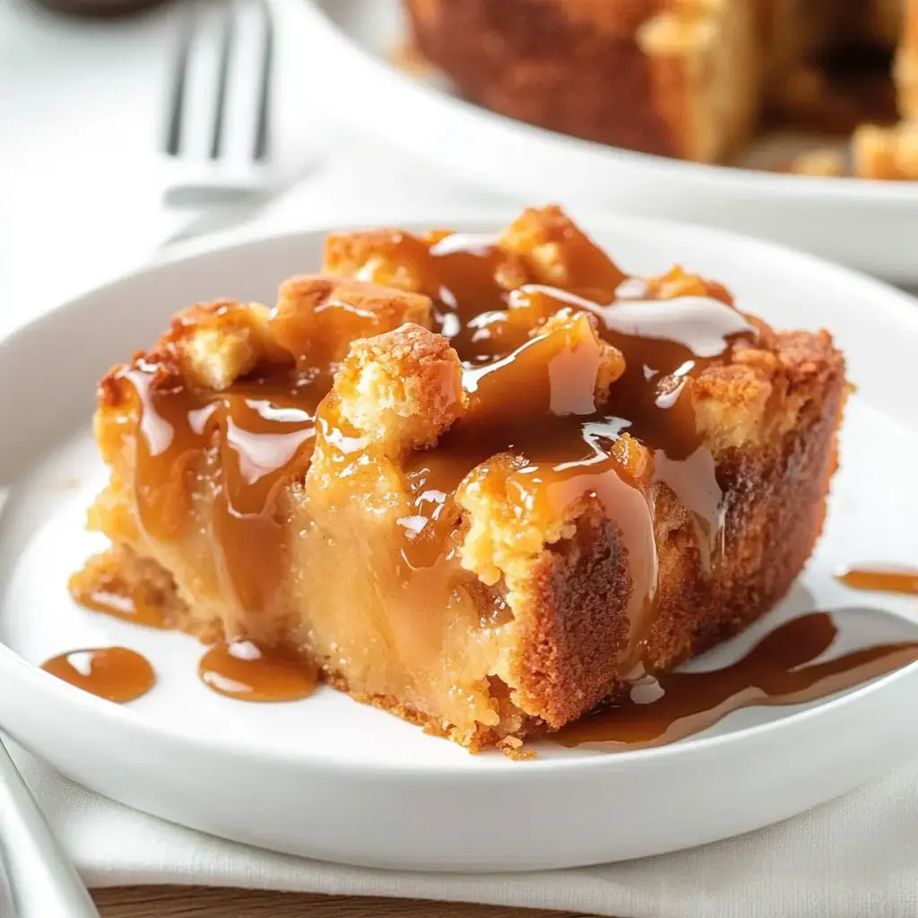 A slice of caramel apple cake dripping with caramel on a white plate.