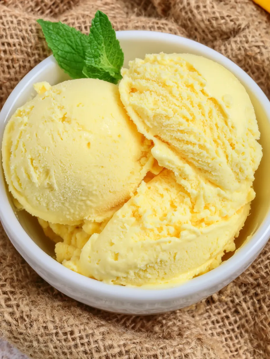 A bowl of yellow ice cream with a mint leaf on top.