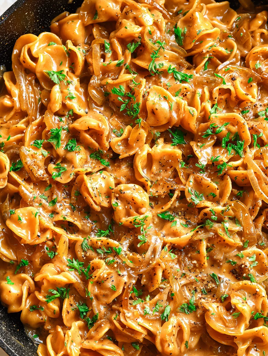 Eine Schüssel mit Pasta, die mit Parmesan und Zwiebeln garniert ist.