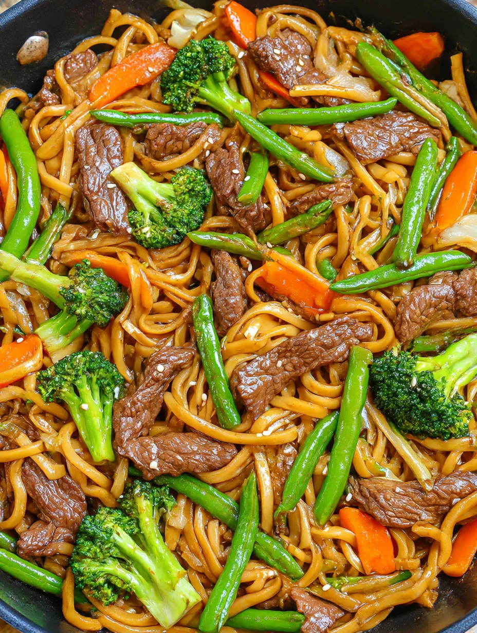 A close up of homemade beef and broccoli lo mein with shiny noodles and crisp veggies.