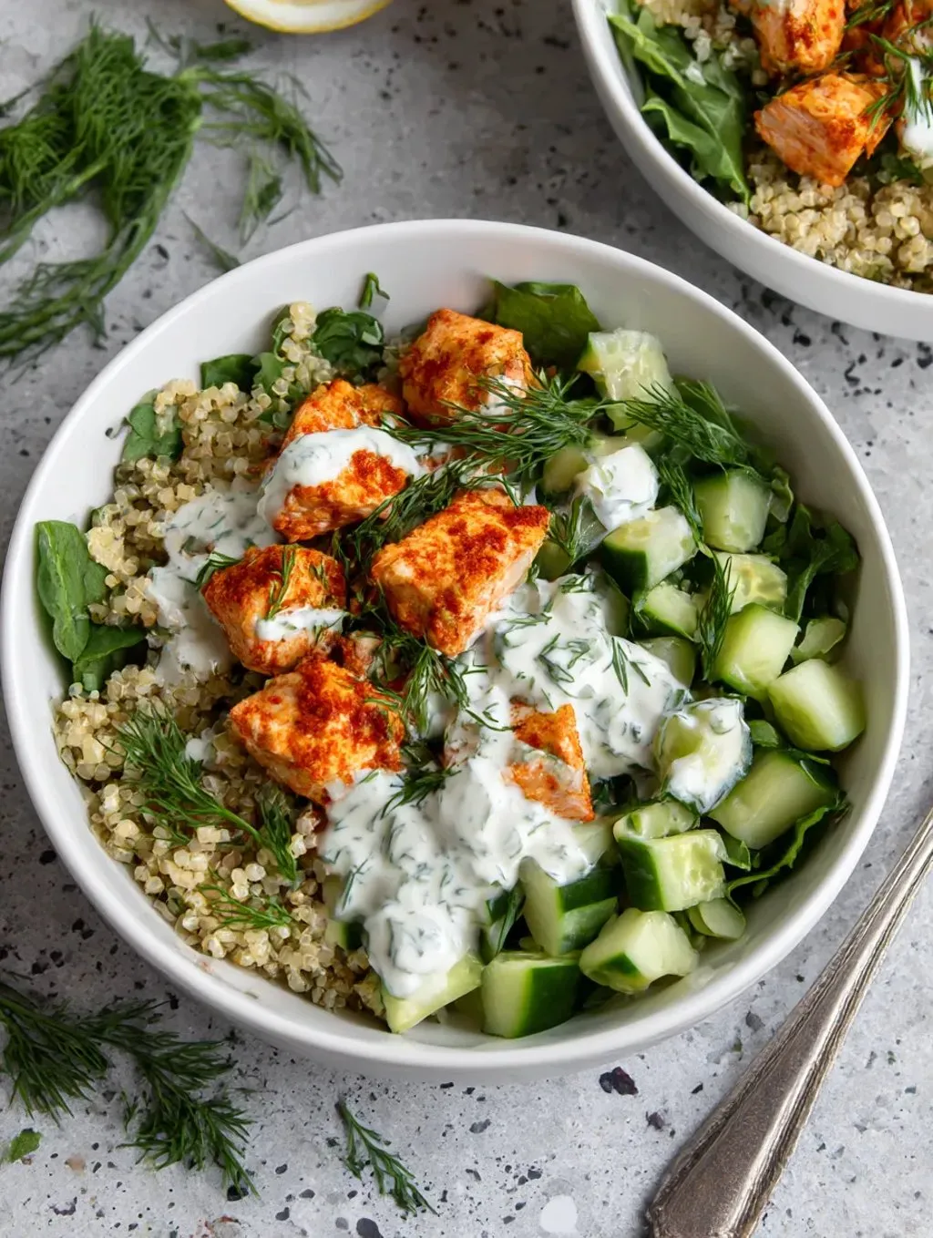A white plate stacked with onions, chickpeas, zucchini, cucumber, and a creamy dressing.