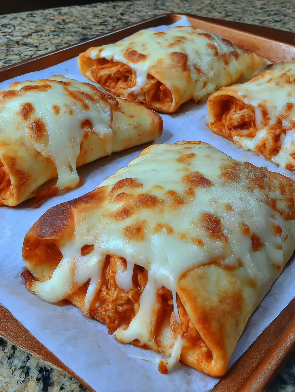A pizza filled with cheese and chicken on a plate.