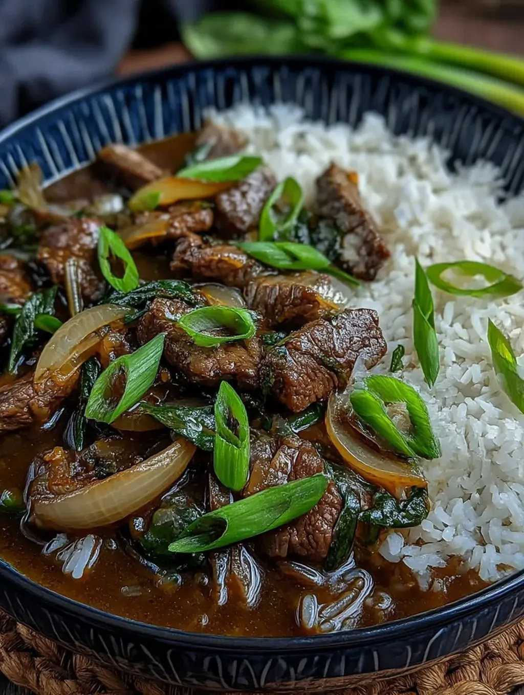 Chinese-style beef and onion stir fry on a black plate.