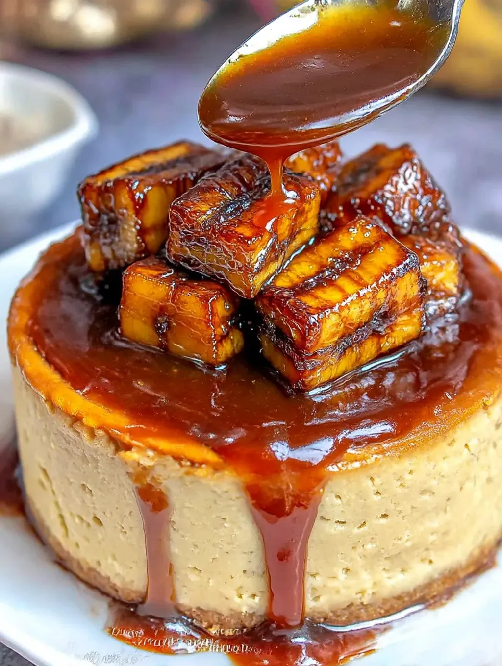 A banana cheesecake topped with caramel glaze, on a white plate.