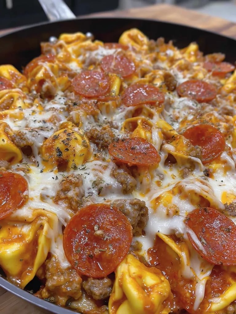 A bowl of pizza-style pasta with tomatoes, mozzarella, and cheese.