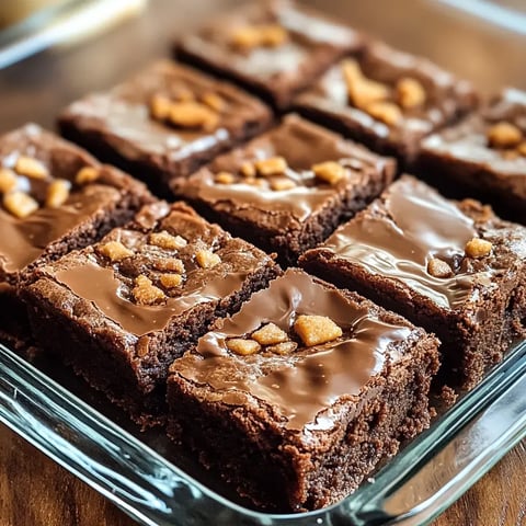 Close-up of glossy chocolate brownies with caramel bits on top.