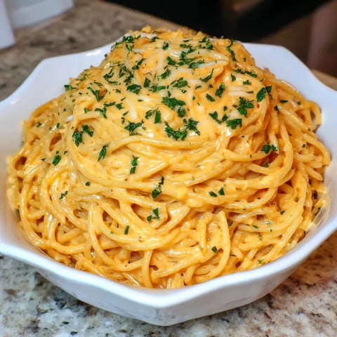 A white plate piled with spaghetti, cheese, and plenty of parmesan and garlic on top.