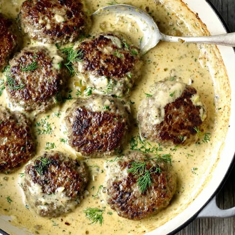 A Dutch oven filled with creamy sauce and beef patties.