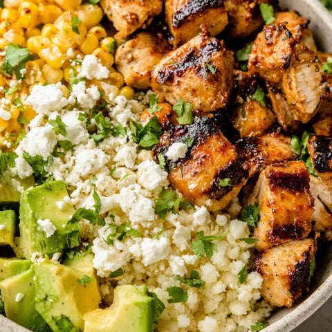 A big bowl loaded with colorful veggies like avocado, potatoes, corn, onions, and steak.