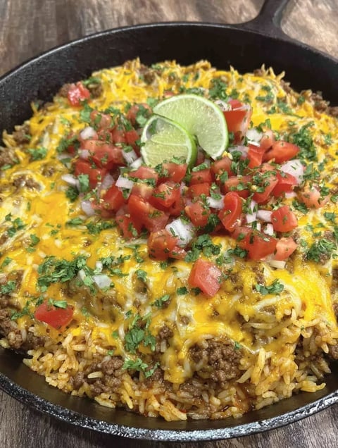 A bowl featuring cheese, tomatoes, lime, and rice all together.