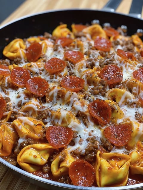 A bowl of pizza goodness made with ravioli, cheese and tomatoes.