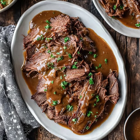 A bowl of steak slices covered in gravy sits on a table.